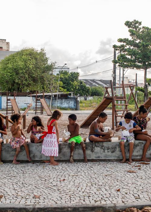 A group of children of various ages sitting together on a cement bench in Recife, Brazil.