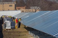 two workers examine solar panels.