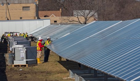 two workers examine solar panels.