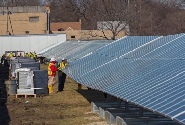 two workers examine solar panels.