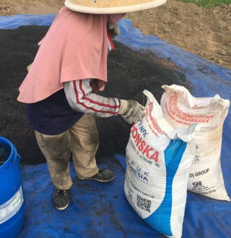 A farmer with large sacks of biochar.