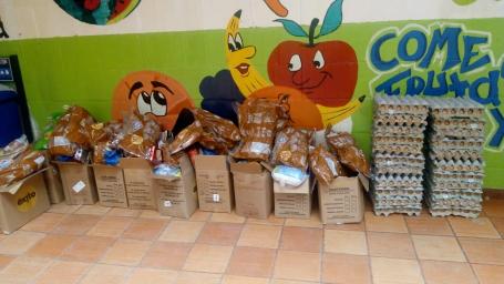 A large stack of donated food in bags and cardboard boxes.