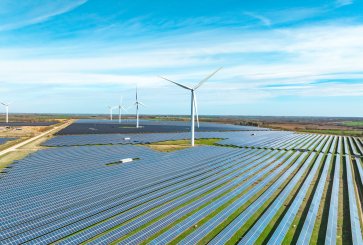 A landscape in England with fields of solar panels and wind turbines.