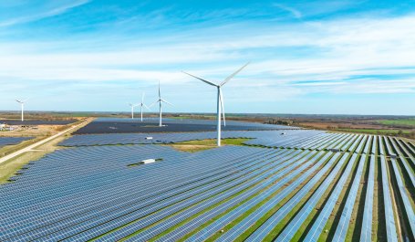 A landscape in England with fields of solar panels and wind turbines.