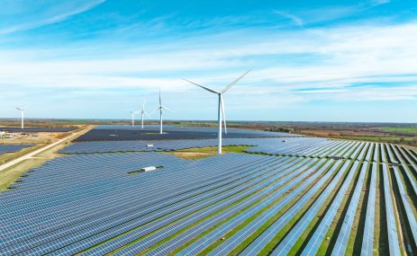 A landscape in England with fields of solar panels and wind turbines.