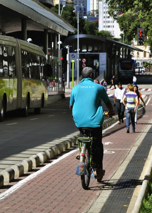 Pedestrians walking and cycling in protected lane alongside bus route.